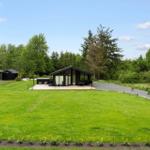 Modern wooden cabin with large garden and terrace. Surrounded by trees and greenery.