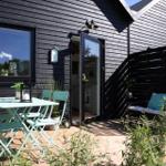 Terrace with table, chairs, and swing in front of black wooden house