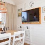 Dining room with table, chairs, wall clock, and TV in wooden frame.