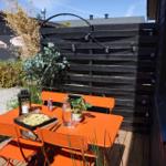 Orange table and chairs on terrace with plants and seating areas.