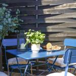 Blue table and chairs with plants and food in the garden.