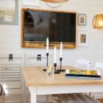 Dining room with wooden table, white chairs, and TV mounted on the wall.