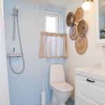 Bathroom with shower, toilet, and sink. Wall with basket decor.
