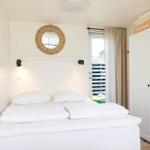 Bedroom with white bed, wall mirror, and wardrobe.
