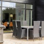 Außenbereich mit Esstisch, Stühlen und Grill. Durchgang ins Innere des Hauses.