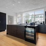 Moderne Küche mit Kücheninsel, integriertem Kühlschrank und großem Fenster.