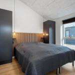 Schlafzimmer mit Bett, zwei Schränken und Holzpaneelen an der Wand.
