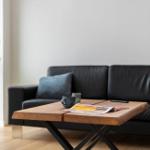 Schwarzes Sofa mit Kissen, Holztisch und Pflanze im Wohnbereich.