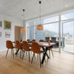 Esszimmer mit Holzboden, Tisch und Stühlen, großen Fenstern und Wandbildern.