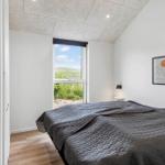 Schlafzimmer mit Blick auf Grasland, graues Bett und Wandbild.