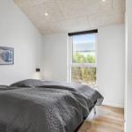 Schlafzimmer mit Bett, Fenster und Holzboden. Wandbild und Deckenleuchte sichtbar.
