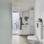 Badezimmer mit Toilette, Waschbecken und Spiegel. Dusche mit Glaswand.