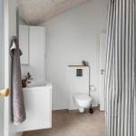 Badezimmer mit Waschbecken, Toilette und Dusche mit Streifenvorhang.