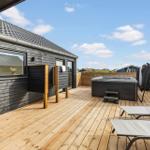 Terrasse mit Whirlpool, Liegestühlen und Holzverkleidung. Blick auf die Umgebung.