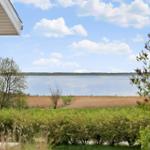 From the terrace, a calm lake with grassland and trees is visible.