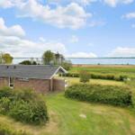 A small house with garden and view of a lake under blue sky.