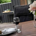 Außenbereich mit Tisch, Stühlen, Grill und Blumenvase.