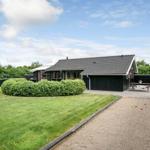 Ein Haus mit Garten, Terrasse und Grillplatz. Ein Weg führt zum Eingang.