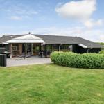 Moderne Villa mit großem Garten und Terrasse mit Sonnenschirm und Liegestühlen.