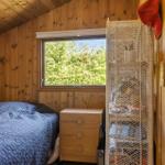 Bedroom with wooden walls, bed, and window with view of trees.