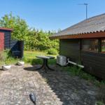 Outdoor area with table, plants, and wooden house under blue sky.