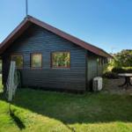 Wooden house with garden, terrace, and table. Outdoor area with lawn and trees.