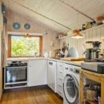 Kitchen with wooden walls, window, sink, stove, and washing machine.