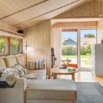 Living room with sofa, coffee table, and wood paneling. Doorway to terrace with garden view.