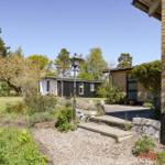 House with garden, terrace, and plants. View of modern architecture and greenery.