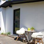 House with terrace, two white chairs and table with plant.