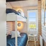 Schlafzimmer mit Doppelstockbett, Fenster und Stuhl.