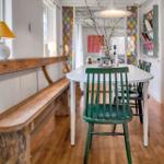 Dining area with green chair and wooden bench. Colorful glass walls and wooden floor.