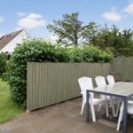 Terrace with table and chairs, surrounded by fence and greenery.