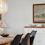 Dining room with wooden table, black chairs, and wall paintings.