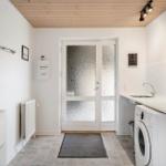 Entrance area with washing machine, sink, and decorative mirror on the wall.