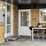 Patio with table, chairs, and coffee mugs. Yellow brick wall and white door.