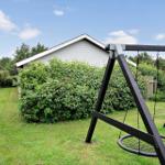 Swing in the garden in front of a house with hedge and grass