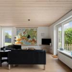 Living room with black sofa, Europe map on wall, and large window to outside.