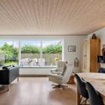 Living and dining area with wooden floor, large windows, and dining table with chairs.