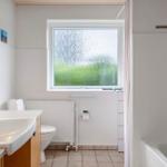 Bathroom with shower, toilet, and sink. Window with green view.