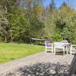 Deck with table, chairs, and hammock setup in the green.