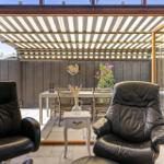 Two black leather chairs face a glass door to an outdoor area with a table and chairs.