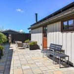 Terrace with seating and plants in front of a house with wooden siding.