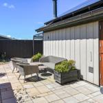 Terrace with seating, plants, and wooden door. Backyard with fence and flowerbed.