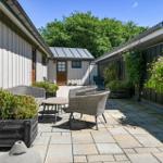 Garden with seating, plants, and stone pavers between buildings.
