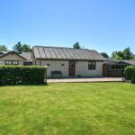 A vacation home with lawn, hedge fence, and wooden veranda under blue sky.