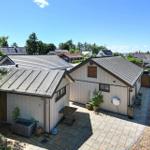House with terrace, plants, and garage. View of residential area and water.