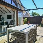 Terrace with table and chairs, view into house with kitchen and living area.