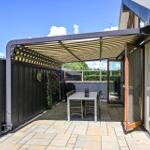 Terrace with awning, table and chairs. Backyard with wooden railing and garden.