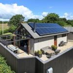 Modern villa with solar panels and terrace. Garden area with seating.
